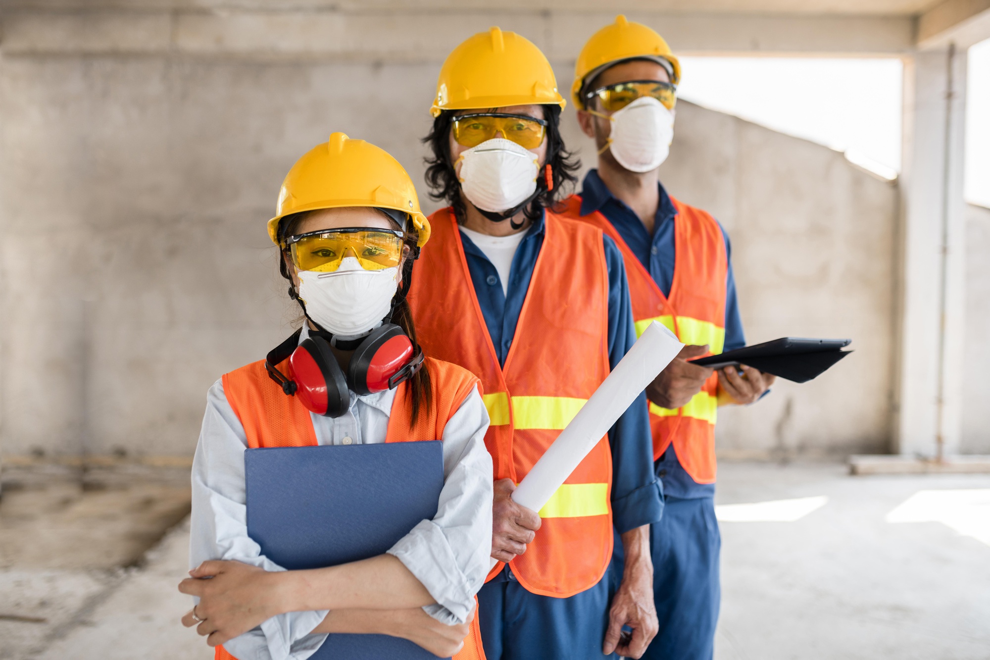 colleagues-with-safety-equipment-working-with-blueprints