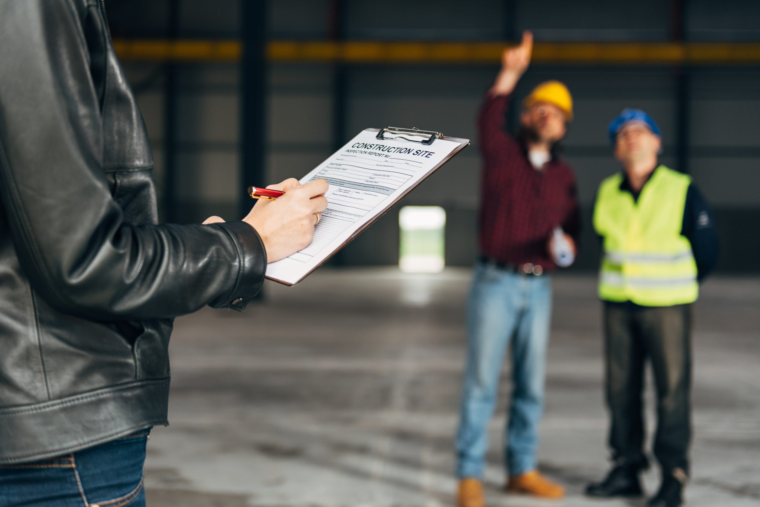 Site Inspector making inspection report in big industrial hall