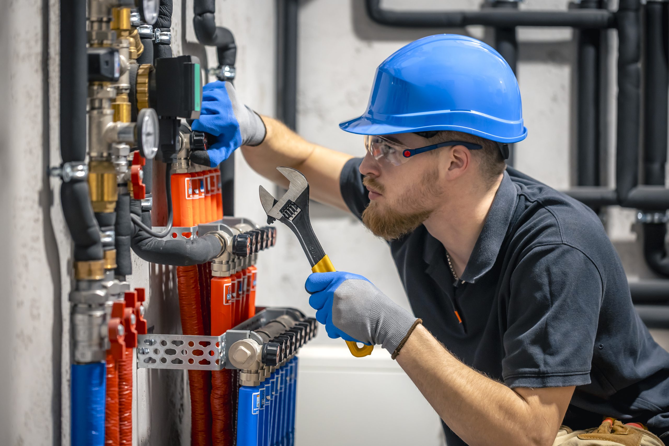 The technician checking the heating system in the boiler room. Adjusting heating valves in a residential building. A plumbing and heating technician works.